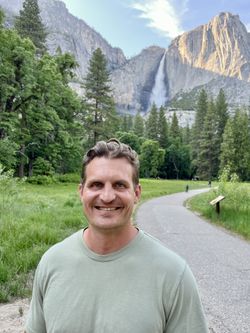 Stetson Ramey standing in a meadow in Yosemite with Yosemite Falls in the background.